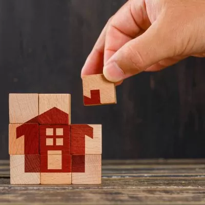 Stay at home concept on wooden background side view. hand holding wooden cube. IMOBILIÁRIO